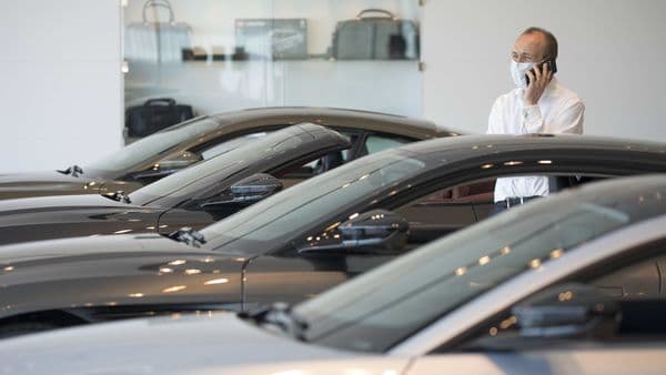 A salesman wearing a protective face mask speaks on a mobile phone at the Aston Martin Works dealership in Newport, UK. (File photo)