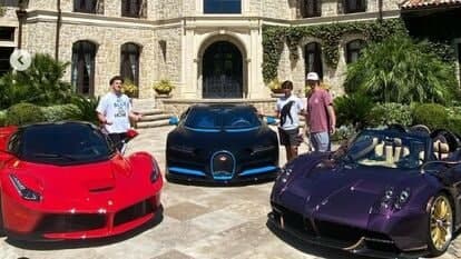 YouTuber Donald Dougher posing with his collection of luxury vehicles.