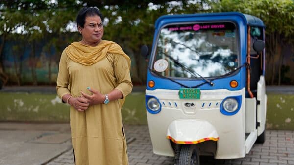 Preethi, a 38-year-old transgender woman who uses only her first name, stands next to her electric auto rickshaw. She's now one of millions of electric vehicle owners in India, but one of very few to have received an EV through a charitable donation. (AP Photo/Aijaz Rahi)