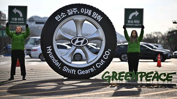 Greenpeace activists hold placards next to a model of a wheel with writing that reads 'Hyundai, Shift Gears! Cut C02' during a protest near the Hyundai Motor Group company's headquarters in Seoul on November 29.